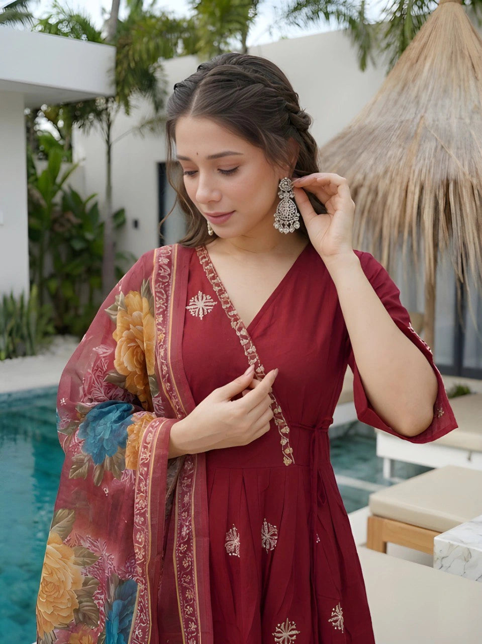 Woman adjusting earrings outdoors by a pool